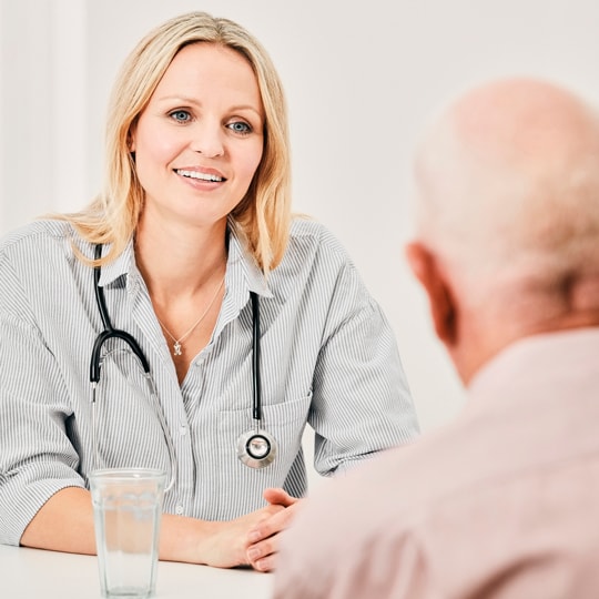 General practitioner with stethoscope around their neck in consultation with senior client.